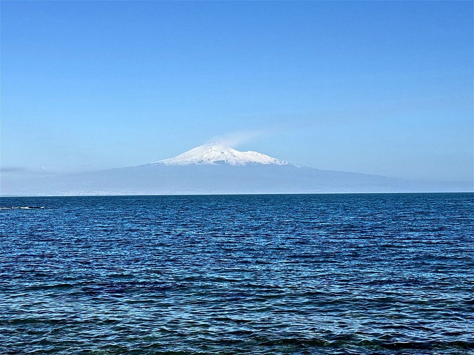 L'Etna innevato all'orizzonte, oltre il mare aperto