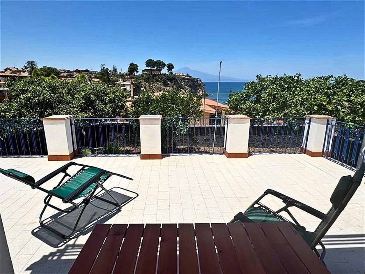 Terrazza con sdraio e tavolo in legno, vista mare