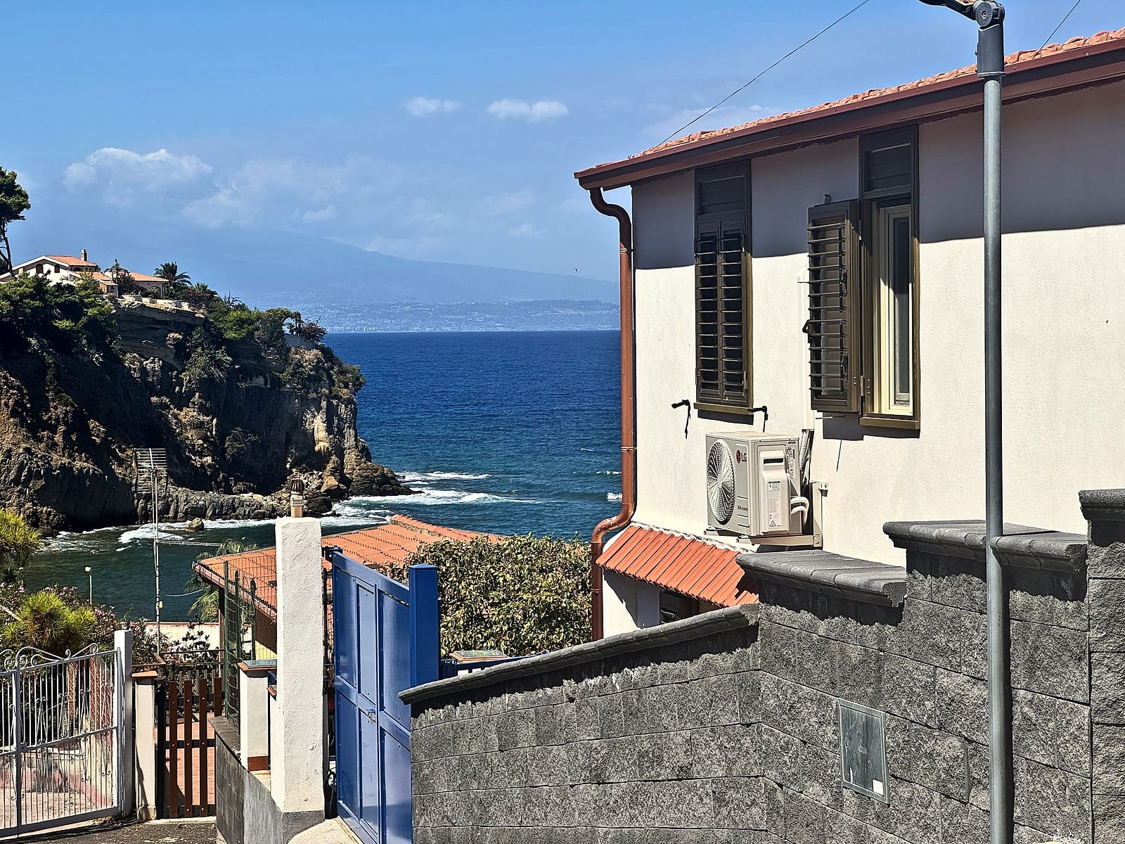 La villa di Etna Lemon Sea con il cancello blu, la scogliera, il mare e l'Etna all'orizzonte